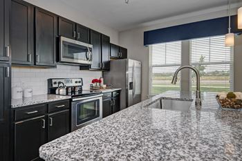 Kitchen with granite counter tops and black cabinets and stainless steel appliances